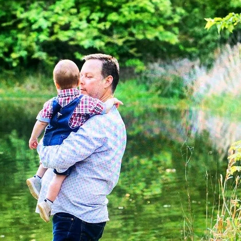 Jim Ikey holding a grandchild outdoors