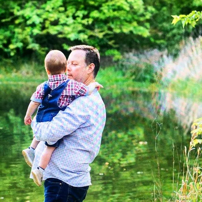 Jim Ikey holding a grandchild outdoors